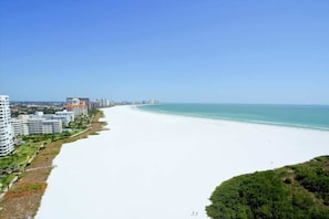 A coastal cityscape with a wide beach, high-rise buildings, and clear skies. - Beautiful SST3 beachfront condo. (Marco Island)