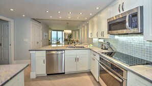 Una cocina moderna con armarios blancos, electrodomésticos de acero inoxidable y una isla grande con pileta.