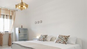 Une chambre à coucher moderne avec un grand lit, une table de chevet, une armoire et une suspension au design géométrique.
