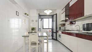 Une cuisine moderne avec des meubles blancs, un plan de travail en granit et un coin repas avec des chaises blanches.
