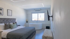 Ein modernes Schlafzimmer mit einem großen Bett, einer runden Badewanne und einem Fenster mit Blick auf die Stadt.