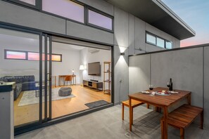 A modern interior with a dining area, a sofa, and a TV in the background. - StayCentral Brunswick Central Townhouse  (Brunswick)