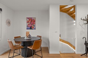 Cozy dining area with a round table and four comfortable chairs, featuring a vibrant abstract painting and a stylish floor lamp.
