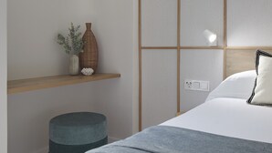 Une chambre à coucher moderne avec un lit, une table de chevet et une étagère fixée au mur.