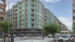 Un immeuble résidentiel à plusieurs étages, doté de balcons, d’un espace de stationnement et d’un passage piéton.