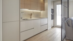 Une cuisine moderne avec des meubles blancs, une partie supérieure en bois et un four encastré.