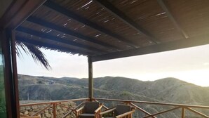 A wooden deck with outdoor seating and a view of a mountainous landscape. - Villa-neem. Amplia, Cómoda y Tranquila (Piura)