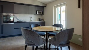 Una cocina moderna con gabinetes grises, un microondas integrado y una mesa redonda de madera con cuatro sillas.
