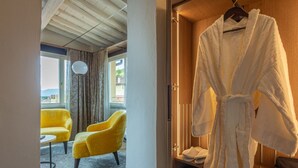 Habitación de hotel con techo de madera, una bata blanca colgada en un perchero y dos sillones amarillos.