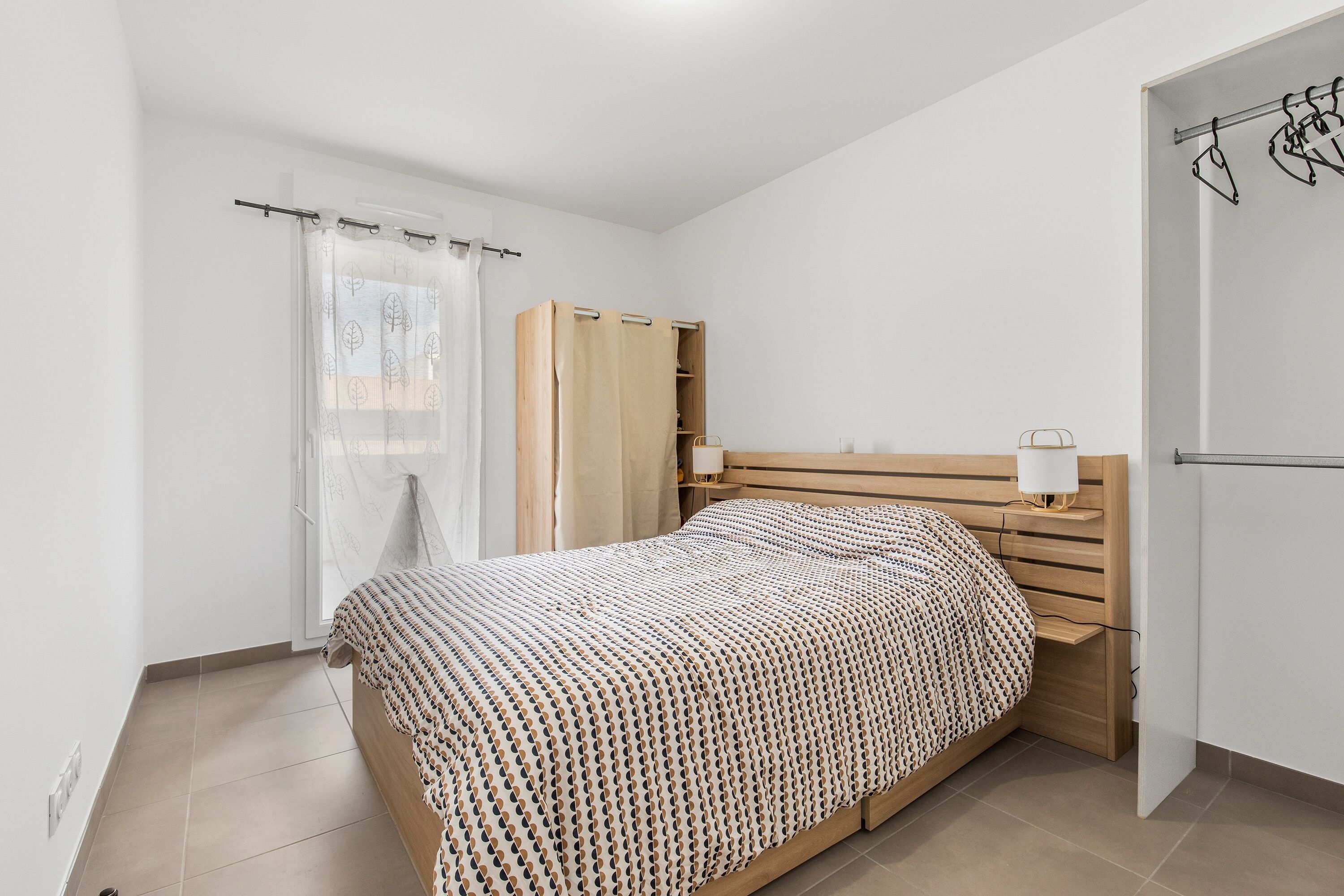 Ein Schlafzimmer mit einem Bett, einem Holzkopfstück, einem Nachttisch und einem Kleiderschrank.