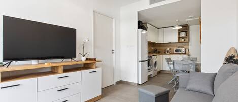 A modern living room with a flat-screen TV, a grey sofa, and a wooden entertainment unit.