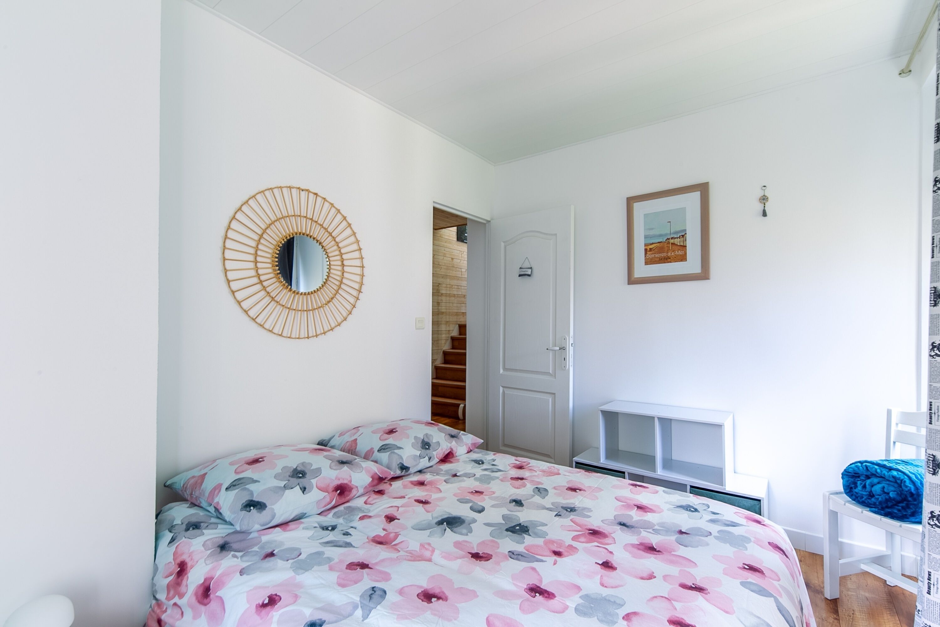 Ein Schlafzimmer mit einem Bett, einem Spiegel, einem gerahmten Bild und einer Treppe, die zu einer oberen Etage führt.