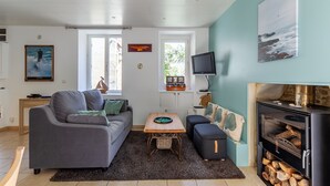 Un salon moderne avec un canapé gris, une petite table, un téléviseur et une cheminée.