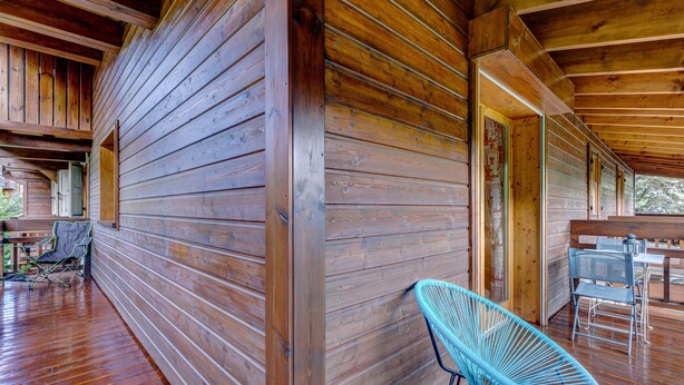 Una cabaña de madera con un porche cubierto, una silla azul y una mesa.