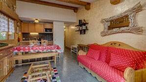 Una habitación acogedora con una mesa de madera, un sofá rojo y una zona de cocina con armarios de madera y un microondas.