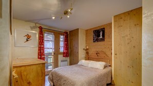 Un dormitorio acogedor con cabecera de madera, una cama con almohada blanca mullida, un aparador de madera y un cuadro enmarcado en la pared.