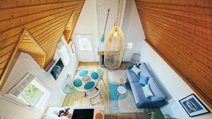 Un intérieur moderne avec un plafond en bois, un coin repas comprenant une table ronde et des chaises, un canapé bleu et un luminaire suspendu.
