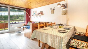 A dining area with a table set for four, wooden chairs, a bench, and a view of greenery outside. - Le Flocon de Pauline - Sur les pistes (Chamrousse)