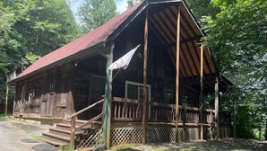 A rustic wooden cabin with a porch, steps, and a fenced area. - Hilltop Hideaway in the Nacoochee Village (Helen)