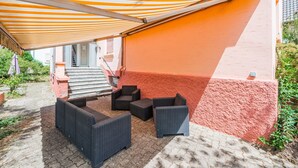 An outdoor patio area with wicker furniture and a striped awning. - L'Adeline - Charmant appartement (Lingolsheim)