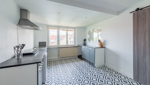 A modern kitchen with a geometric patterned floor, a built-in stove, and a window providing natural light. - L'Adeline - Charmant appartement (Lingolsheim)