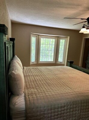 Une chambre à coucher avec un lit, une fenêtre et un ventilateur de plafond.