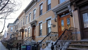 A row of brick townhouses with ornate iron railings and a fire escape. - Luxurious Apartment at Colonial Townhouse (Queens)
