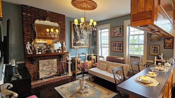 A cozy living room with a fireplace, a sofa, and a dining area with a long table. - Luxurious Apartment at Colonial Townhouse (Queens)
