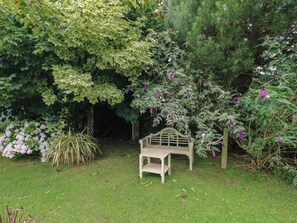 A wooden bench in a garden with various plants and trees. - Llaethdy Cottage (Haverfordwest)