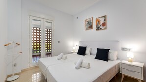 Camera d'albergo con due letti, un comodino con una lampada, un'opera d'arte appesa al muro e una porta con pannello vetro satinato.