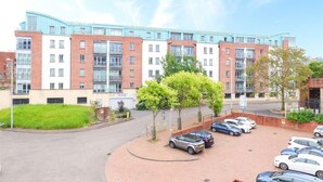 A multi-story residential building with a parking area in front. - Beauchamp House (Coventry)