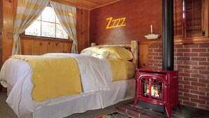 Una stanza accogliente con due letti, una stufa a legna in legno rosso e arredamento in legno.