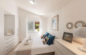 A bedroom with a bed, a bedside table with a lamp, a dresser, and a window with a view.
