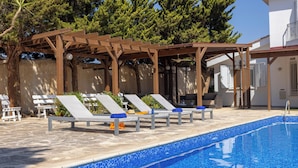 A pool area with lounge chairs and a pergola. - Protaras Apollon Seaside Villa (Protaras)