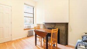 Une pièce avec une table à manger en bois, deux chaises, une porte blanche, une fenêtre et une cheminée.