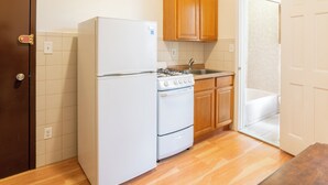 Une cuisine compacte équipée d’un réfrigérateur, d’une cuisinière, d’un four, de placards en bois et d’un évier.
