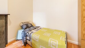 Une petite chambre à coucher, bien rangée, avec un lit, une table de chevet et une armoire en bois.