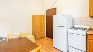 Une cuisine de taille réduite, avec une table en bois, un réfrigérateur, une cuisinière et un placard.