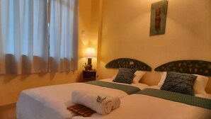 Habitación de hotel con dos camas, una mesita de noche, una lámpara y una obra de arte en la pared.