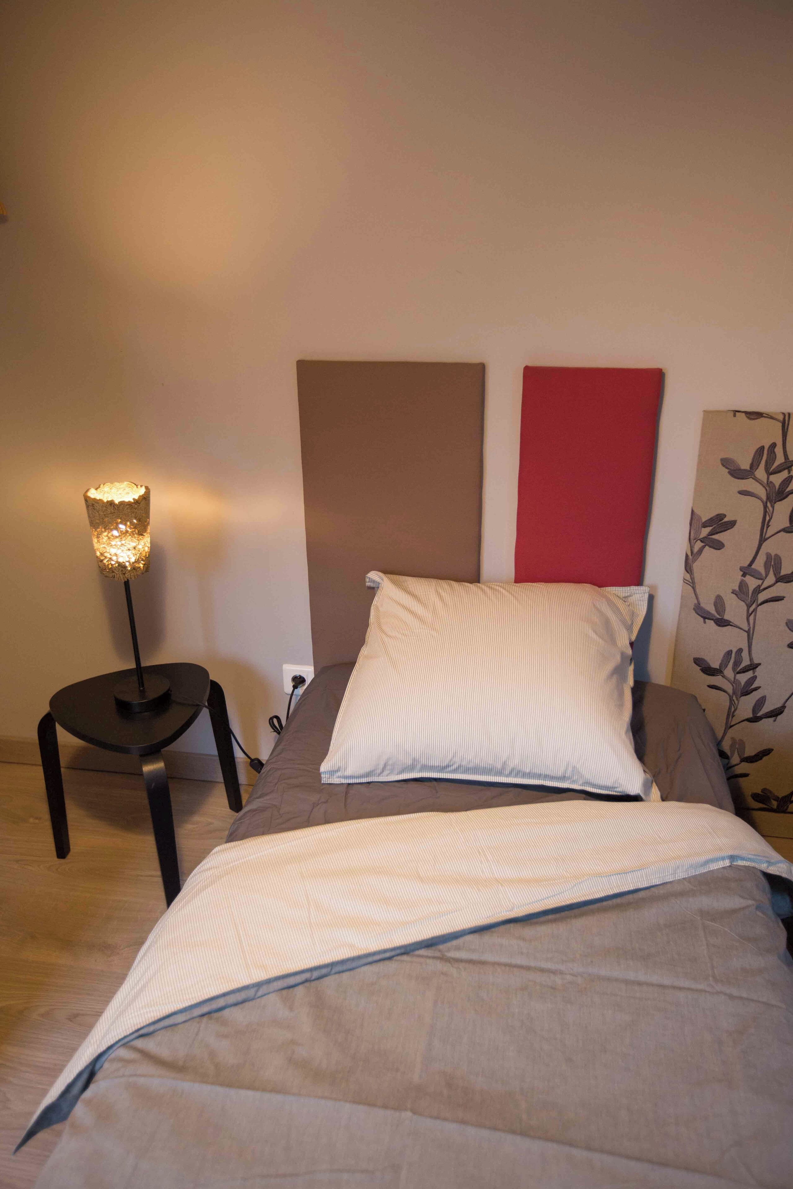 Ein Schlafzimmer mit einem Bett, einer Nachttischlampe und einer Wand mit rotem Paneel.