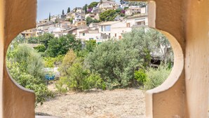 A view through a cut-out window of a hillside town with buildings, greenery, and a clear sky.