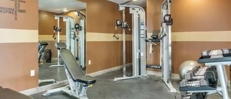 A gym with various exercise equipment, including a bench, weight machines, and dumbbells.