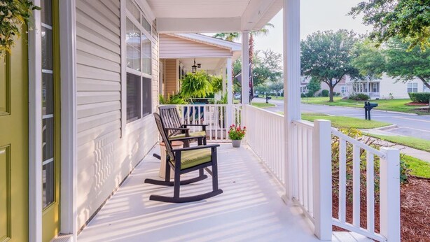 A porch with two rocking chairs, a potted plant, and a white fence. - Calypso Cottage in Old Town Bluffton. Single level home in the heart of historic Old Town (Bluffton)