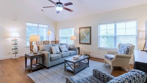 A living room with a sofa, armchairs, a coffee table, and a ceiling fan. - Calypso Cottage in Old Town Bluffton. Single level home in the heart of historic Old Town (Bluffton)