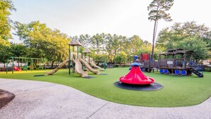 A playground with a slide, climbing structures, and a red circular play area. - Calypso Cottage in Old Town Bluffton. Single level home in the heart of historic Old Town (Bluffton)