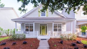 A two-story house with a front porch, white railings, and a green door. - Calypso Cottage in Old Town Bluffton. Single level home in the heart of historic Old Town (Bluffton)