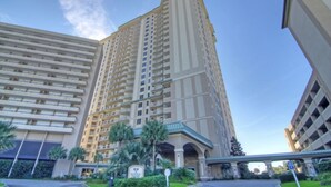 Ein Hochhaus-Hotel mit mehreren Balkonen, einer Beschilderung mit dem Schriftzug "Royale Palms" und einem überdachten Gang.