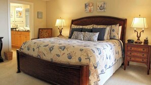 Ein Schlafzimmer mit einem großen Bett, zwei Nachttischen, einem Schminktisch und einem Spiegel.