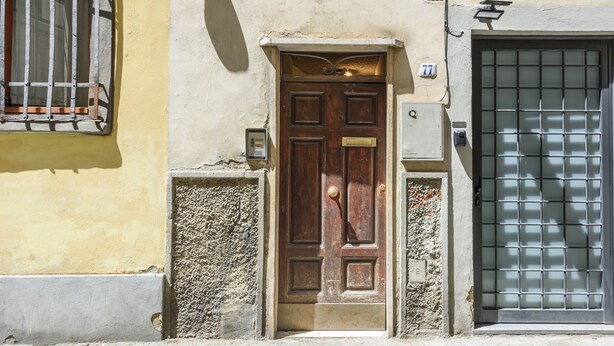A wooden door with a brass handle, a mailbox, and a number plate '77' on the wall. - Artist's Refuge by Mmega (Florence)