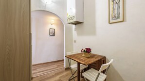 A small dining area with a wooden table, white chairs, and a basket of flowers. - Artist's Refuge by Mmega (Florence)